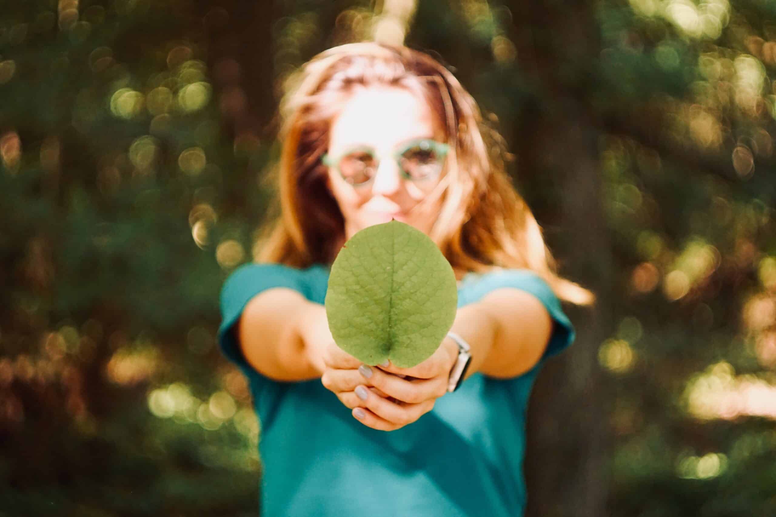 a girl holding a green leaf with both hands